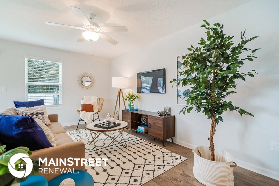 a living room with a couch and a plant and a ceiling fan