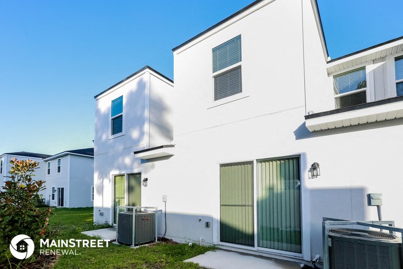 the exterior of a white house with a driveway and grass