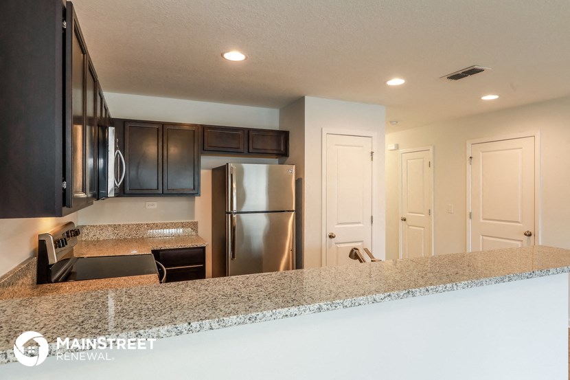 a kitchen with a granite counter top and a stainless steel refrigerator
