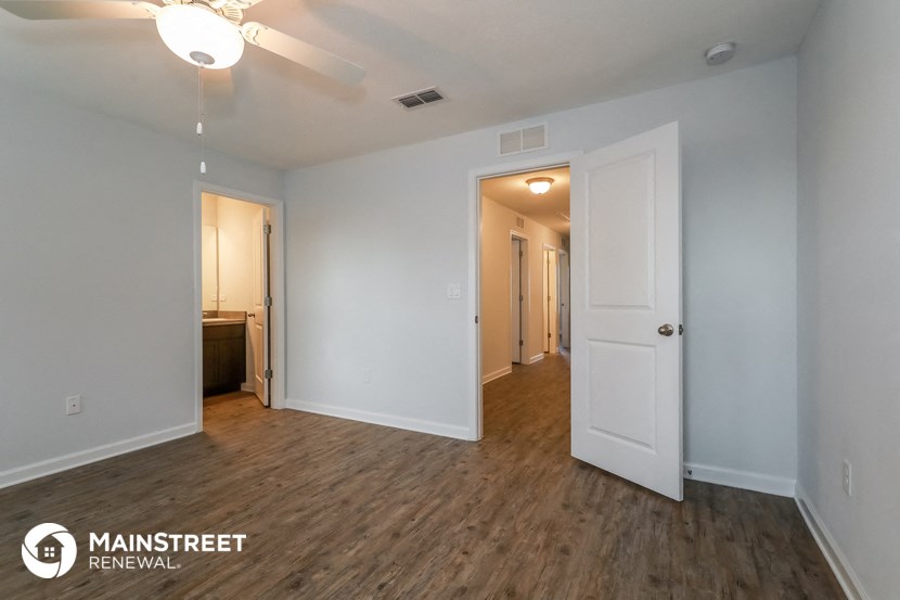 the living room and hallway of an apartment with white walls and wood flooring