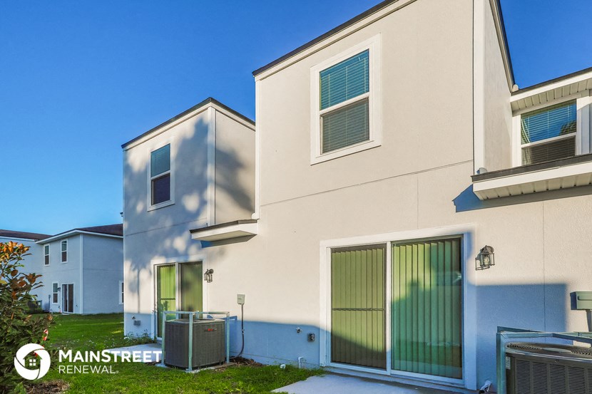 a side view of a house with a driveway and a gate