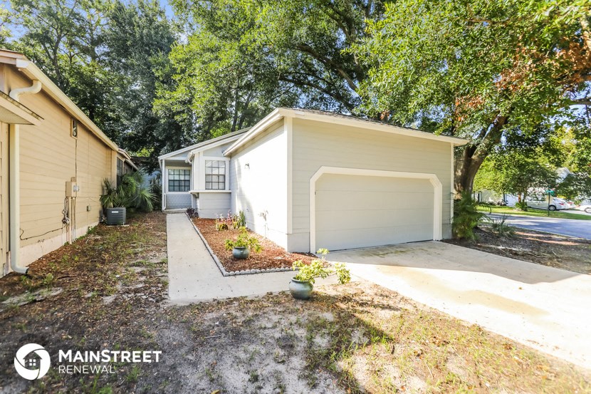 a small white house with a driveway and a garage door