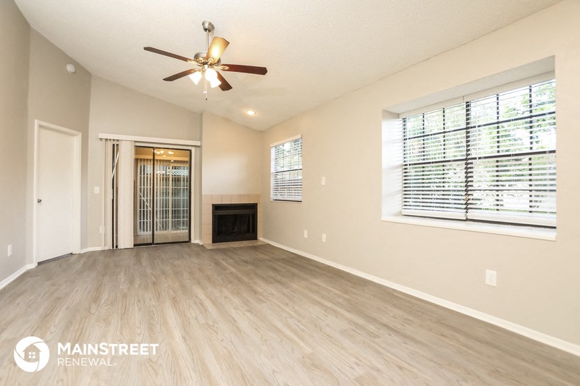 an empty living room with a ceiling fan and a window