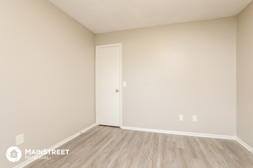 the upstairs bedroom of an apartment with wood flooring and a closet