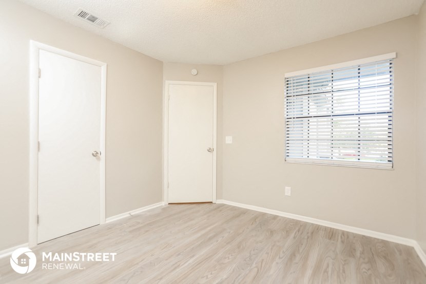 the living room of an apartment with wood flooring and a window