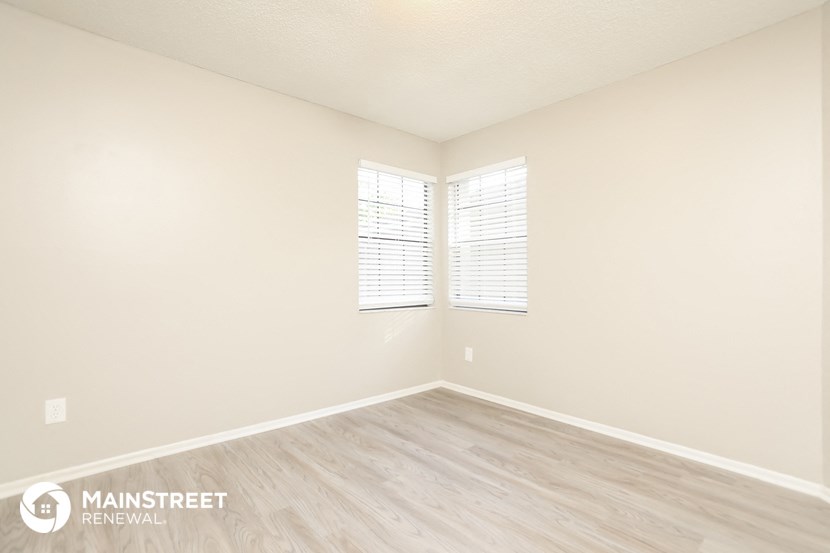 the upstairs bedroom with wood flooring and two windows