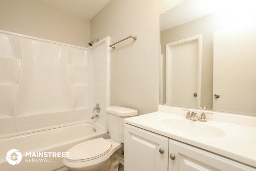 a white bathroom with a toilet sink and tub and a mirror