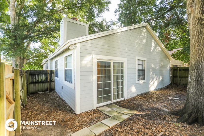 the exterior of a small white house in a backyard with trees