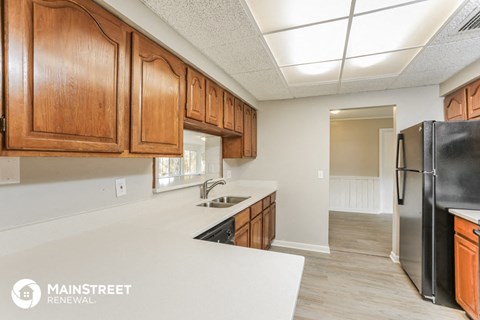 a kitchen with wood cabinets and white countertops and a black refrigerator
