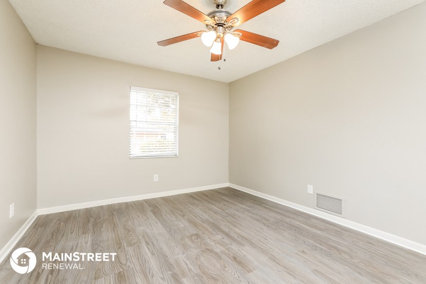 the spacious living room with hardwood flooring and a ceiling fan