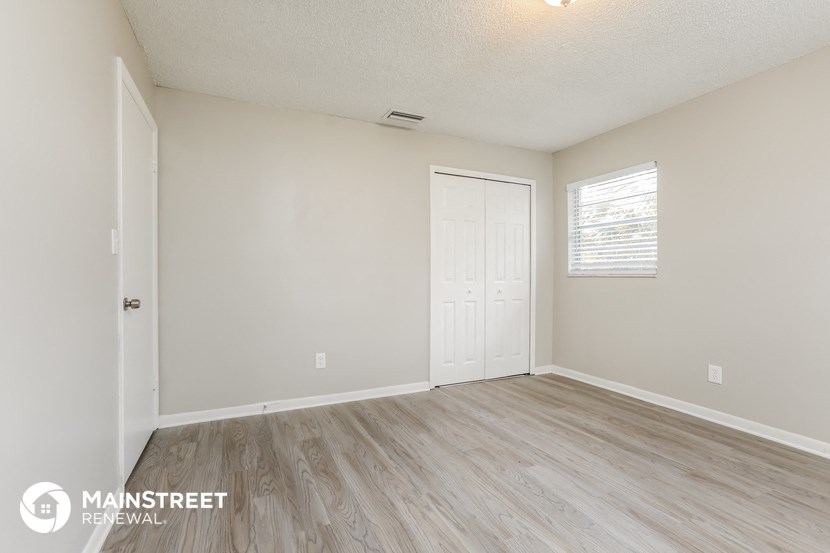 the spacious living room with wood flooring and white walls