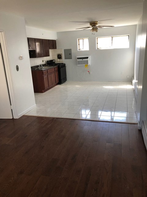 A kitchen with dark wood floors and white walls.