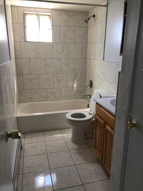 A white tiled bathroom with a toilet, sink, and tub.