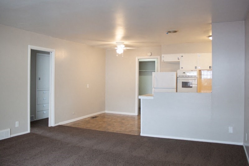 A large empty room with a carpeted floor and a white counter.