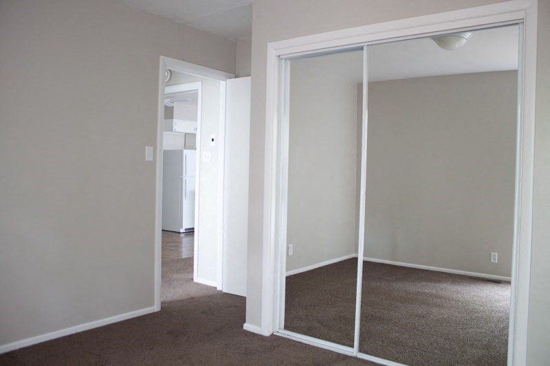 A room with a white door and a carpeted floor.