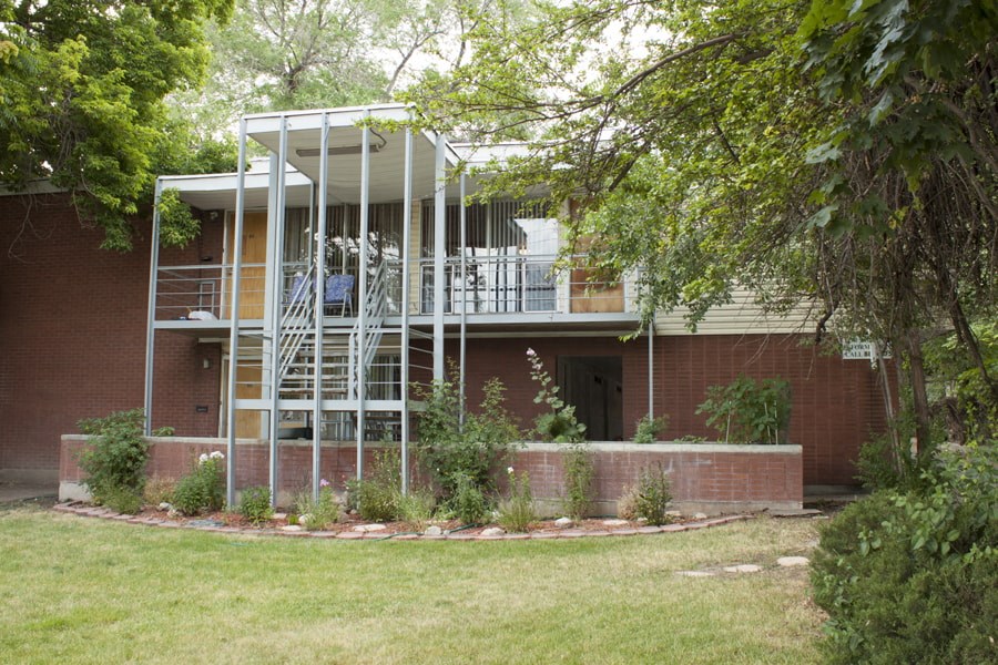 A house with a red brick exterior and a white metal structure on the upper floor.