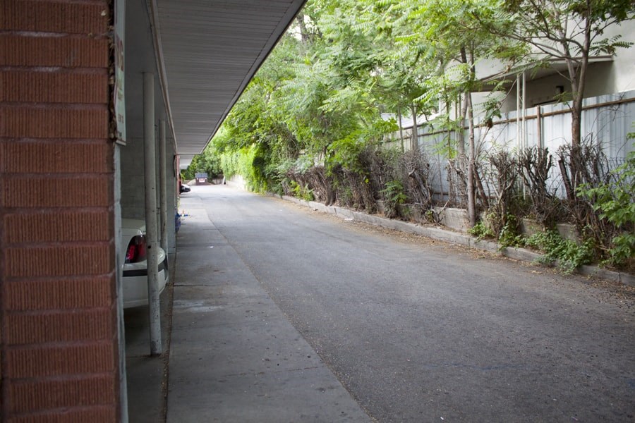 A long, narrow road with a brick wall on one side and a metal fence on the other.