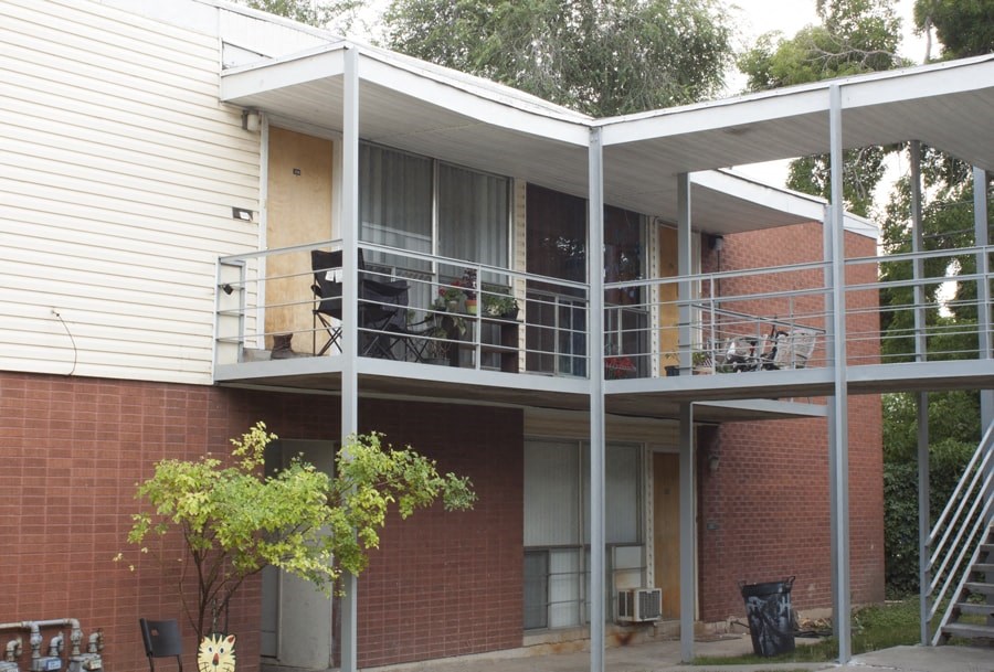 A balcony with a table and chairs is attached to a house.