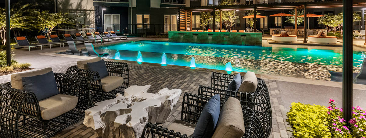 a swimming pool at a hotel with tables and chairs
