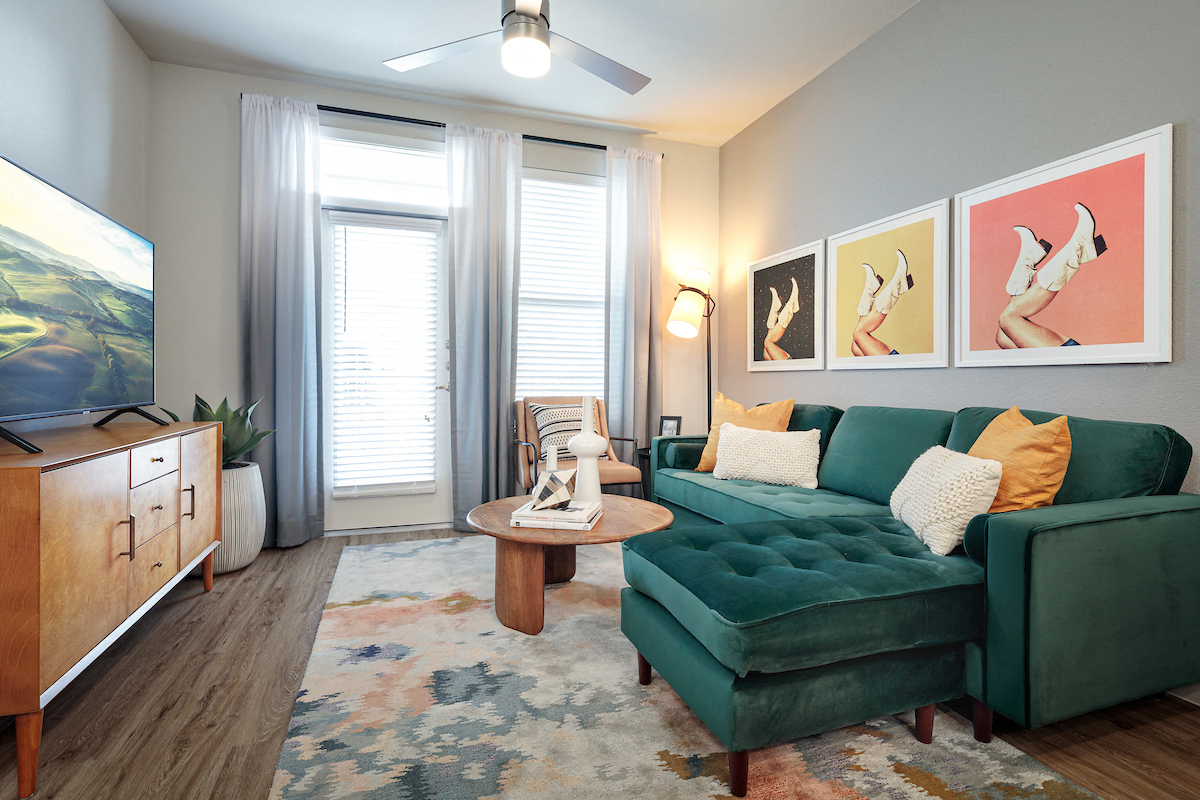 A living room with a green couch and a wooden cabinet.