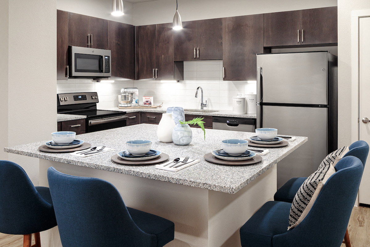 A modern kitchen with a dining table set for two.