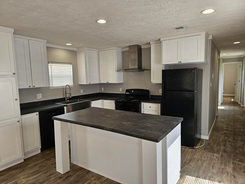 A kitchen with white cabinets and black appliances.