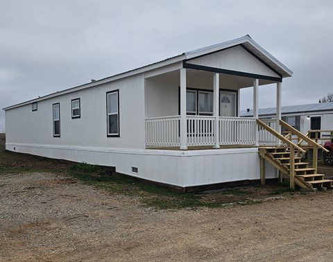 A white mobile home with a porch and a covered patio.