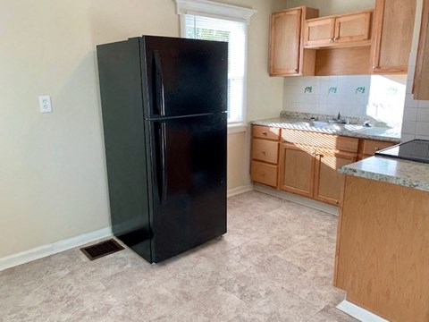 A black fridge in a kitchen with wooden cabinets.