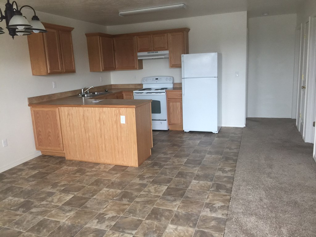 an empty kitchen with wood cabinets and a white refrigerator