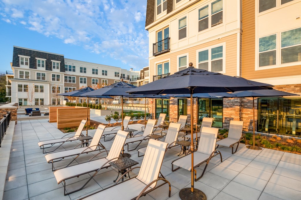 an outdoor patio with chairs and umbrellas at the residences station