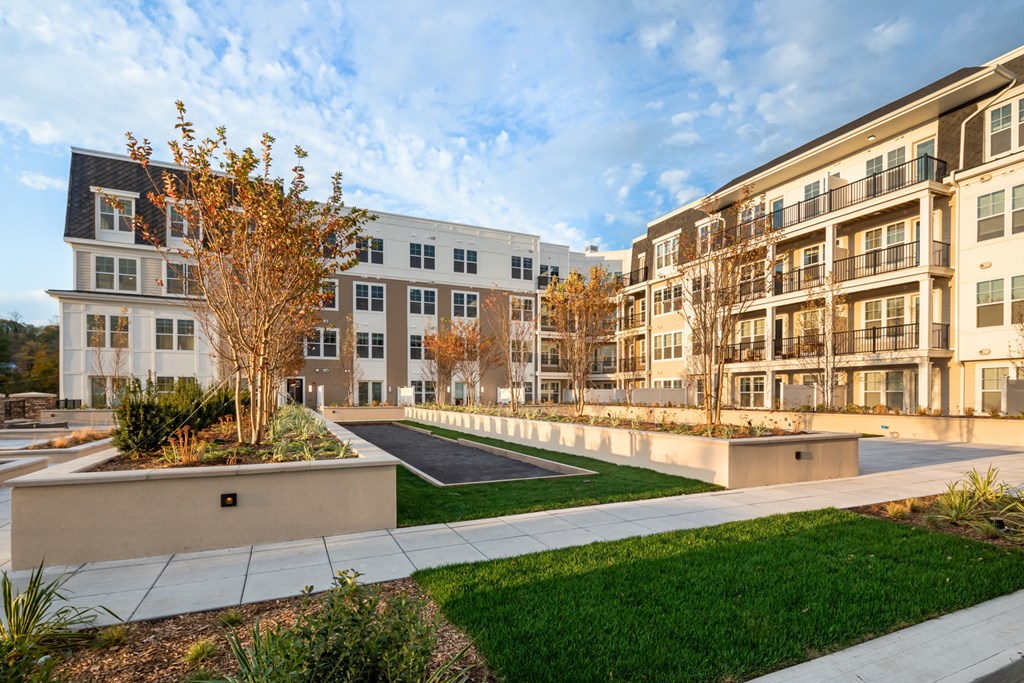 an exterior view of an apartment complex with a courtyard and grass