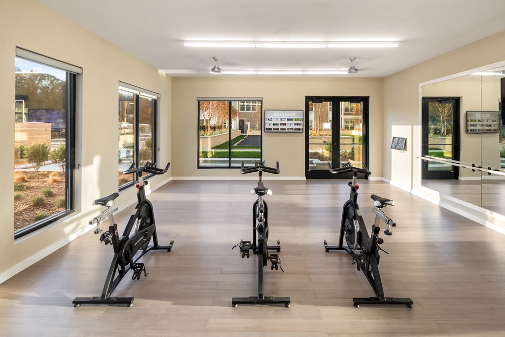 a gym with exercise bikes and windows on the wall