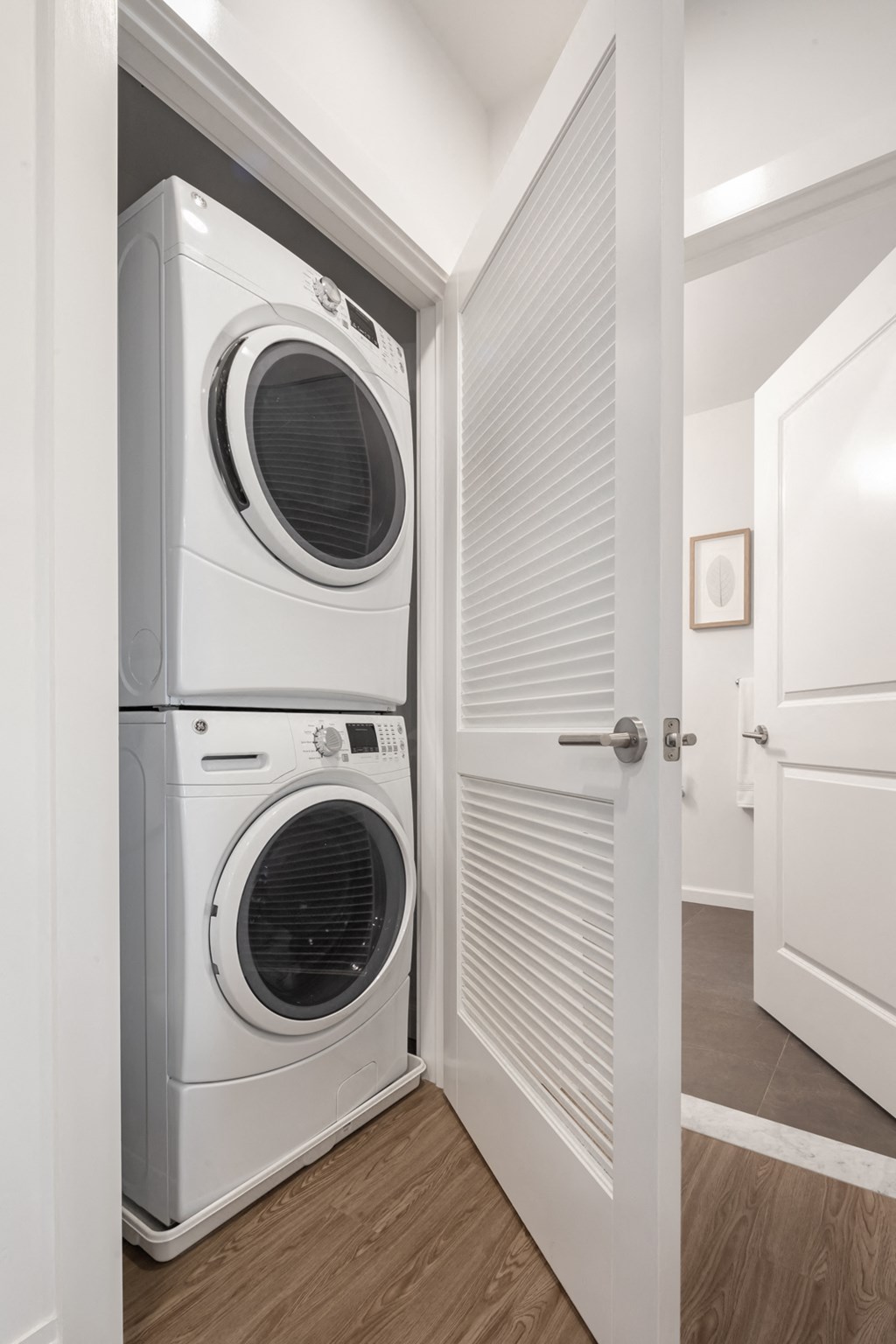 a front loading washer and dryer in a small closet in a white room