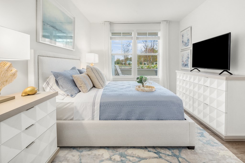 a white bedroom with a bed and a television