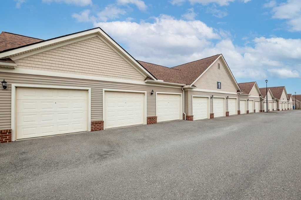 a row of garages with white garage doors and a street
