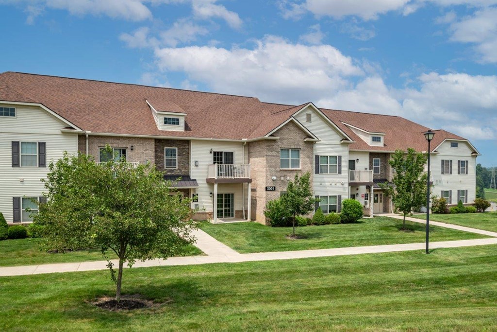 a large apartment building with grass and trees in front of it