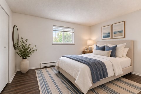 A bedroom with a large bed and a plant on the side table.