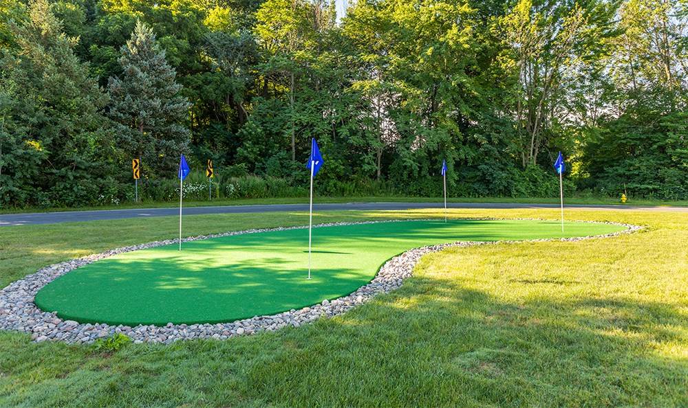 a putting green with blue flags on a golf course