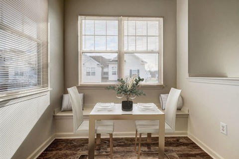 a dining room with a table and chairs and two windows