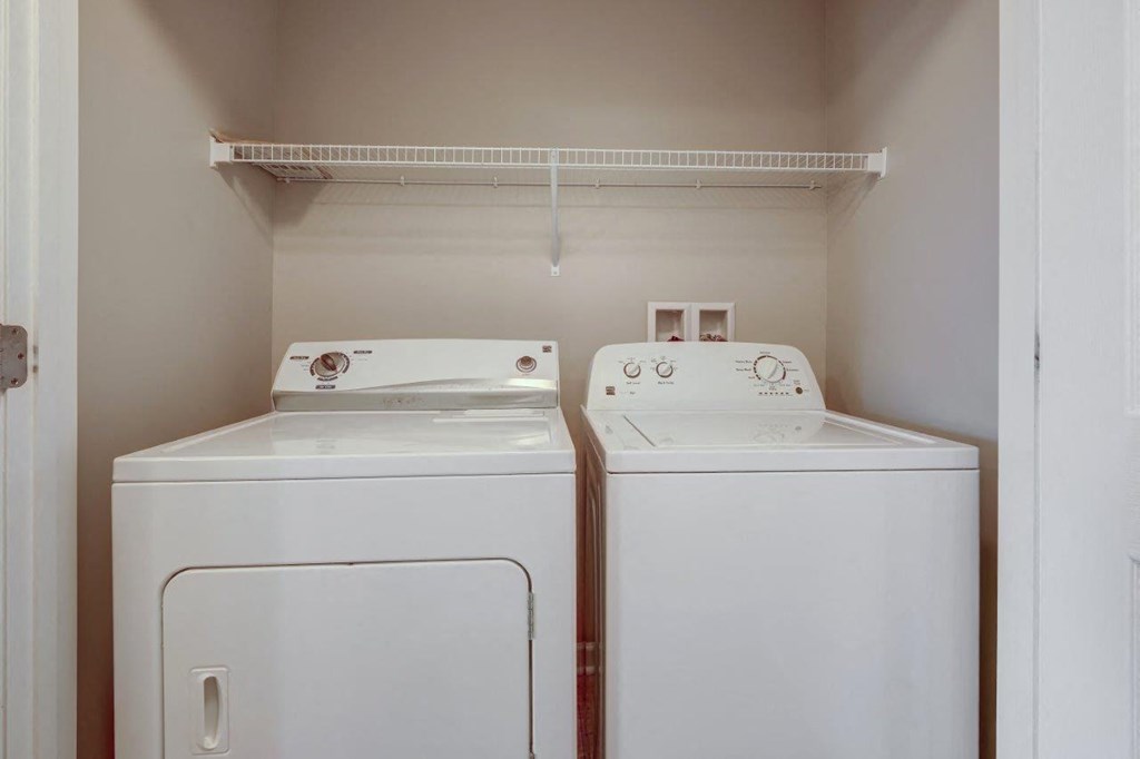 a washer and dryer in a laundry room with a shelf above them