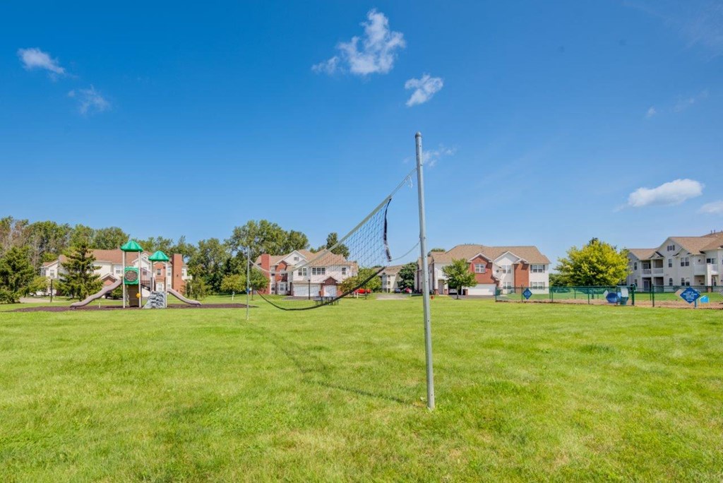 a volleyball court in a park with houses in the background