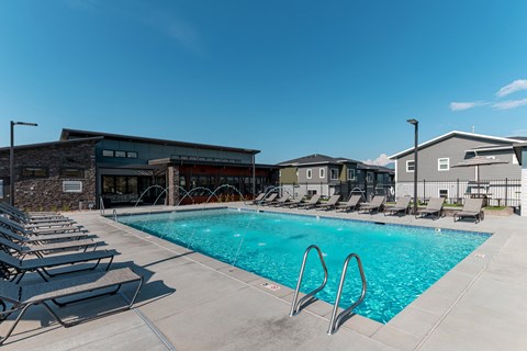 A swimming pool with lounge chairs and a building in the background.