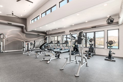A spacious gym with various exercise equipment and a ceiling fan.