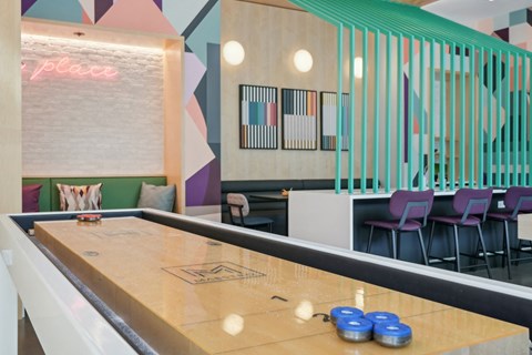 a shuffleboard table in a room with a bar and chairs