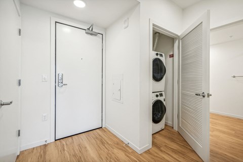 a washer and dryer in a white room with a door to a closet