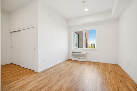 a living room with white walls and wood floors and a window