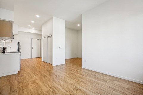 a living room and kitchen with white walls and wood floors