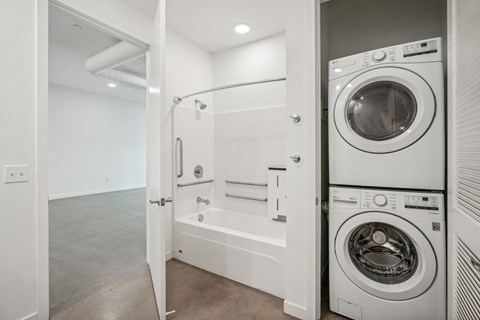 a washer and dryer in a laundry room with a tub and a shower