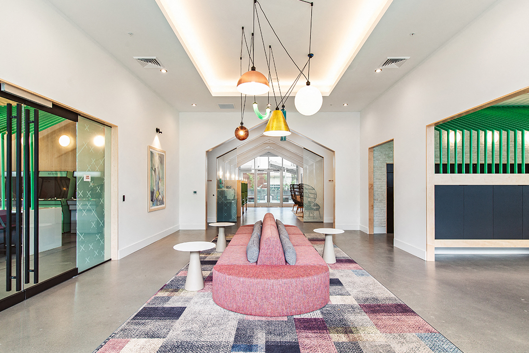 a large lobby with a pink couch and tables and lights