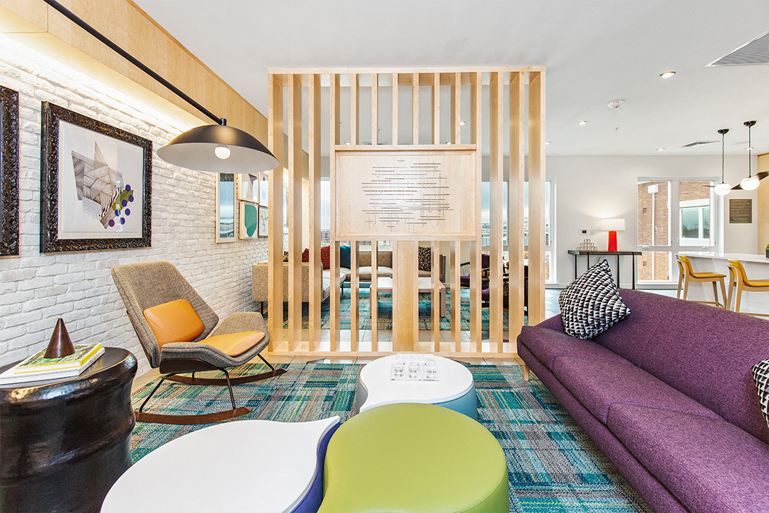 a living room with a purple couch and chairs and a wooden partition